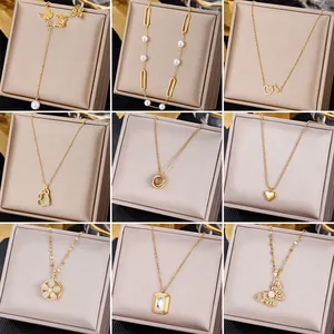 Set of gold stainless steel necklaces with emerald and pearl pendants in elegant jewelry boxes