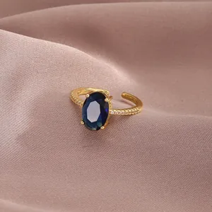 Macro shot of an adjustable gold ring with a large oval blue gemstone on purple silk