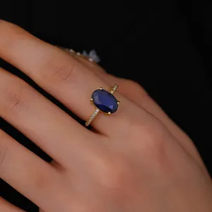Macro detail of a vintage gold ring with an oval blue gemstone and micro-pave diamonds