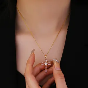 Detalle de collar con cruz dorada y piedras rosas sobre modelo con chaqueta negra