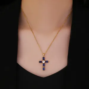 Primer plano del collar con colgante de cruz dorada y circonitas azules rectangulares