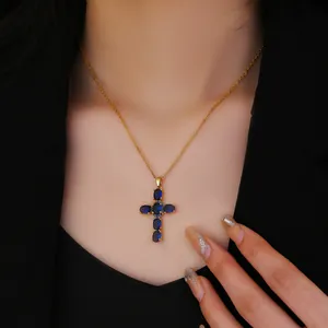Detailed view of golden titanium cross necklace with deep blue cubic zirconia on model neck