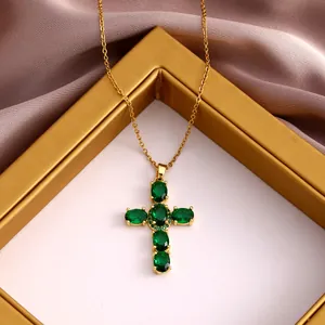 Detail of gold necklace featuring a cross pendant with vibrant green oval-cut cubic zirconia