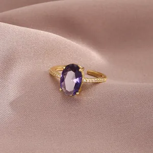 Detail of an oval purple zircon gold ring with accent stones on pink silk fabric