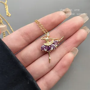 Detail eines goldenen Ballerina-Anhängers mit lila Zirkonia, in der Hand gehalten