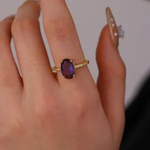Macro shot of an oval purple gemstone ring with gold band and sparkling white crystals