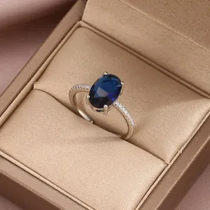 Macro detail of oval dark blue sapphire ring with sparkling white gems on silver band