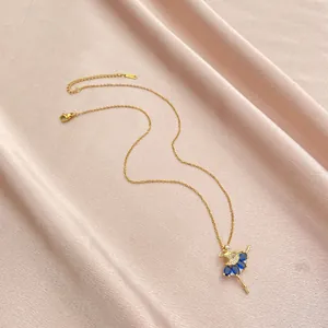 Detaillierte Makroansicht des goldenen Ballett-Anhängers mit blauen Zirkonias auf rosa Satin