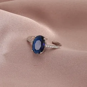 Macro shot of an adjustable silver ring featuring a large oval blue gemstone and side diamonds