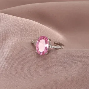 Close-up of pink oval cut gemstone ring with diamond accents on a silk background