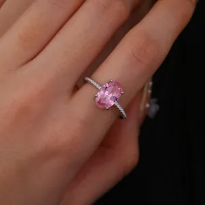 Close-up of hand wearing silver ring with oval pink gemstone and white pavé zircons