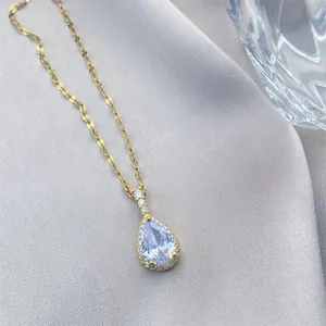 Elegante collar de gota dorado con piedra púrpura y engaste halo sobre fondo de seda