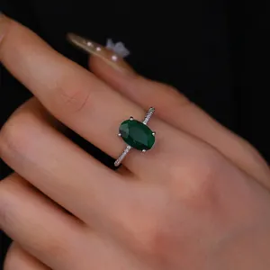 Close-up of luxury oval green gemstone ring with pavé-set zircons on silver band