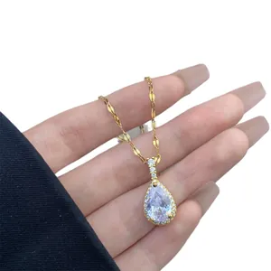 Elegante collar con colgante de gota dorada e incrustaciones de cristal en la mano