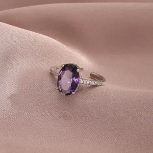 Macro view of adjustable silver ring featuring a large oval purple gemstone and pavé diamonds