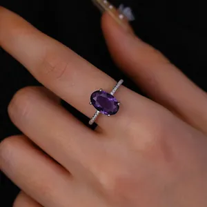 Detail of luxury oval purple gemstone ring with diamond accents on white gold band