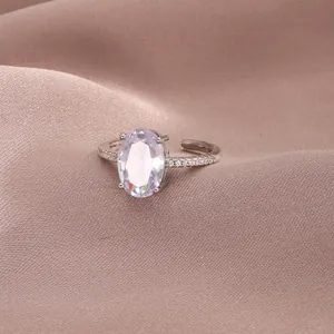 Close-up of luxury silver ring with oval zircon and pavé diamonds on satin fabric