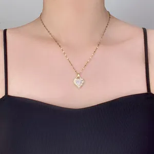 Detalle de collar de acero de titanio dorado con colgante de corazón y circonitas rosas y blancas
