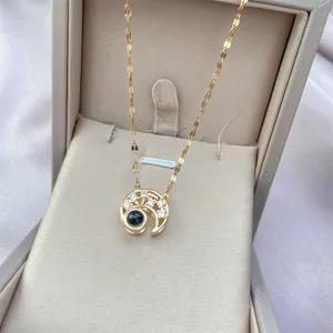 Macro view of gold crescent moon necklace pendant with micro-inlaid stones and projection bead