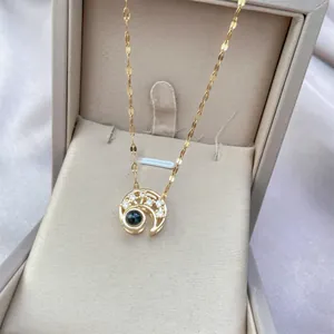 Close-up of golden crescent moon necklace with projection stone in a premium gift box
