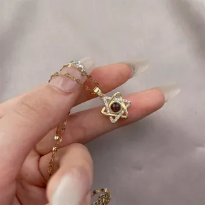 Detail of gold star pendant necklace featuring micro-set zircons and red projection stone