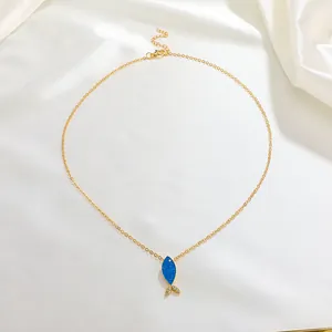 Gros plan d'un collier pendentif poisson bleu avec strass blancs sur tissu de soie