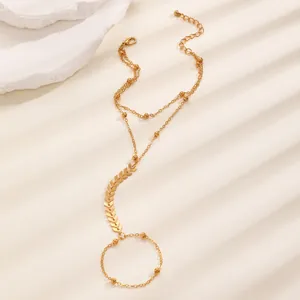 Dettaglio di bracciale anello dorato con doppie catene a perline e maglie a freccia