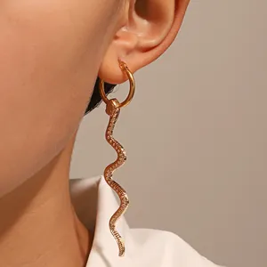 Detailed close-up of golden cobra snake hoop earrings with embossed scale texture on model