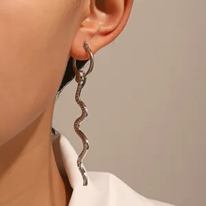 Close-up of a silver cobra snake pendant earring worn on a model's earlobe