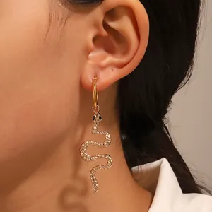 Close-up of a gold snake drop earring with detailed engraving worn by a model