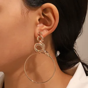 Detail of a large gold hoop earring with a 3D snake link worn by a model in a side view