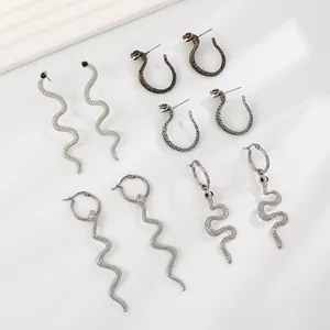Five pairs of punk style cobra earrings in silver and black finishes on white background
