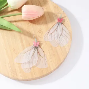 Pendientes largos de borla con alas de cigarra y mariposa de esmalte rosa sobre madera