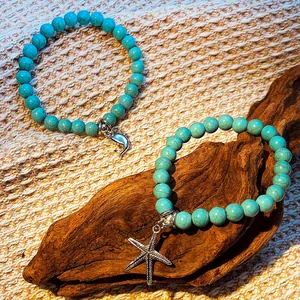 Set de bracelets en turquoise avec pendentifs dauphin et étoile de mer sur bois
