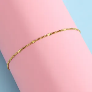 Détail de la chaîne dorée avec perles gravées sur support rose et fond bleu clair