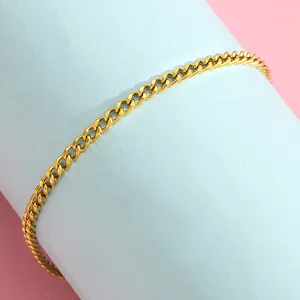 Detailed close-up of a polished gold Cuban chain bracelet wrapped on a blue cylinder