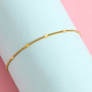 Detail shot of a gold-toned tassel chain bracelet featuring engraved sunburst charms