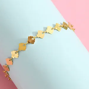 Detailed macro view of golden shell link bracelet featuring textured nautical charms