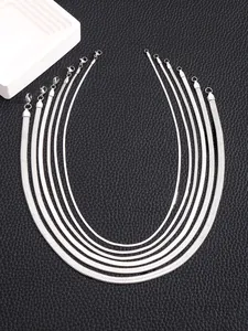 Macro shot of five flat snake bone necklaces in varied widths on black leather background