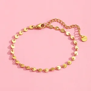 Detailed macro view of gold stainless steel disk chain bracelet with lobster clasp and tag