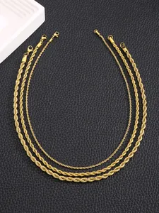 Three gold rope chains of different widths with lobster clasps on black leather background