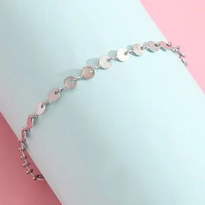 Macro detail of polished stainless steel silver disc tassel chain bracelet for women