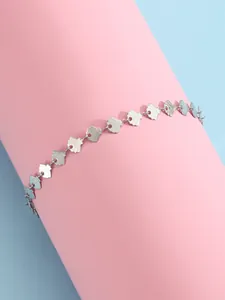 Détail d'une chaîne de cheville argentée à paillettes géométriques sur fond bleu