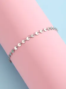 Détail d'une chaîne de cheville à disques argentés entourant un support rose doux