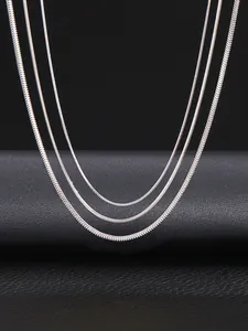 Esposizione verticale di tre catene a serpente in argento con consistenza e lucentezza