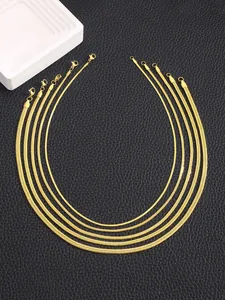 Dettaglio di cinque catene a serpente piatte placcate oro 18k in varie larghezze su nero