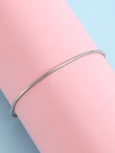 Vue macro d'une chaîne serpent argentée enroulée sur un support rose et fond bleu