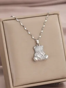 Macro-opname van een zilveren teddybeer hanger met zirkonia en klavertje op een fijne ketting