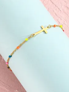Makro-Detail des goldenen Kreuz-Fußkettchens mit bunten Perlen auf blauem Ständer