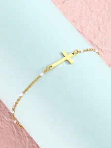 Detailaufnahme des goldenen Edelstahlarmbands mit Kreuzanhänger und weißen Perlen